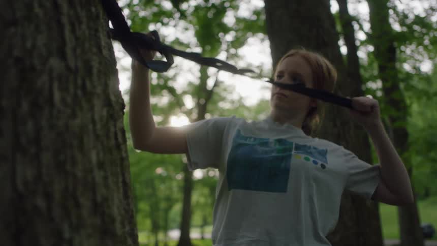 A woman is tying a rope to a tree