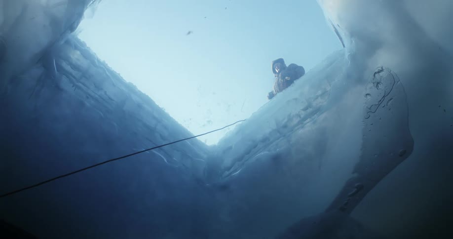 Underwater view of a man on top of the frozen water ice fishing