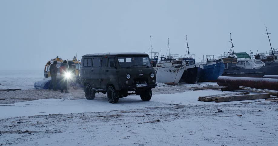 People work on boat at marina as snow falls