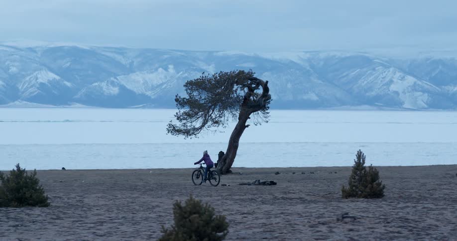 A person bikes along a sandy beach in winter