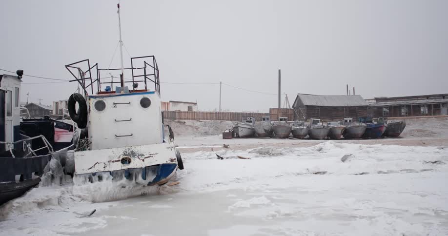Boats on a frozen lake during a snowstorm