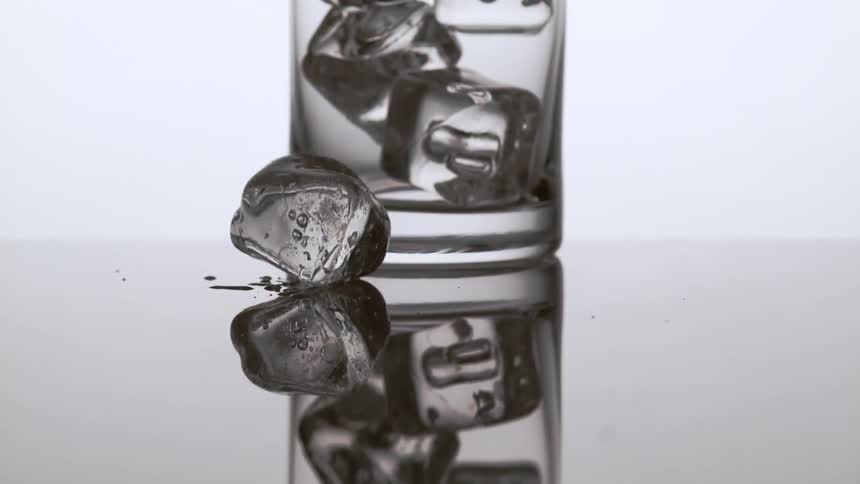Ice dropping in front of a glass filled with ice