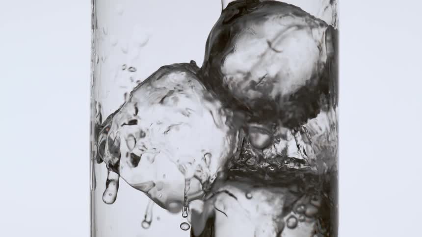Water is poured onto ice cubes in a glass