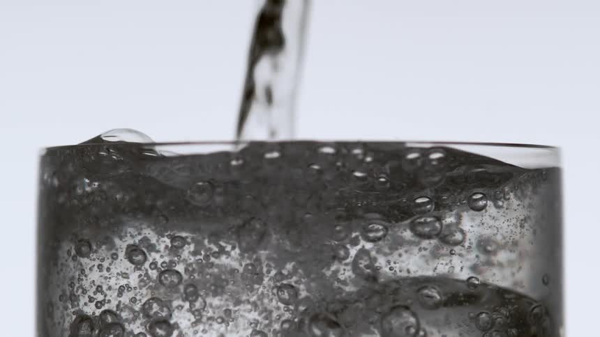 Water pouring over the ice in a narrow drinking glass