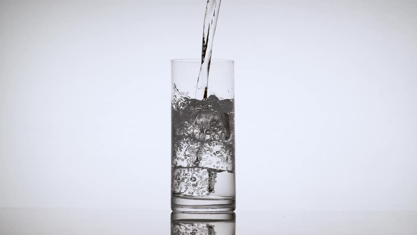 Water pours into a drinking glass filled with ice