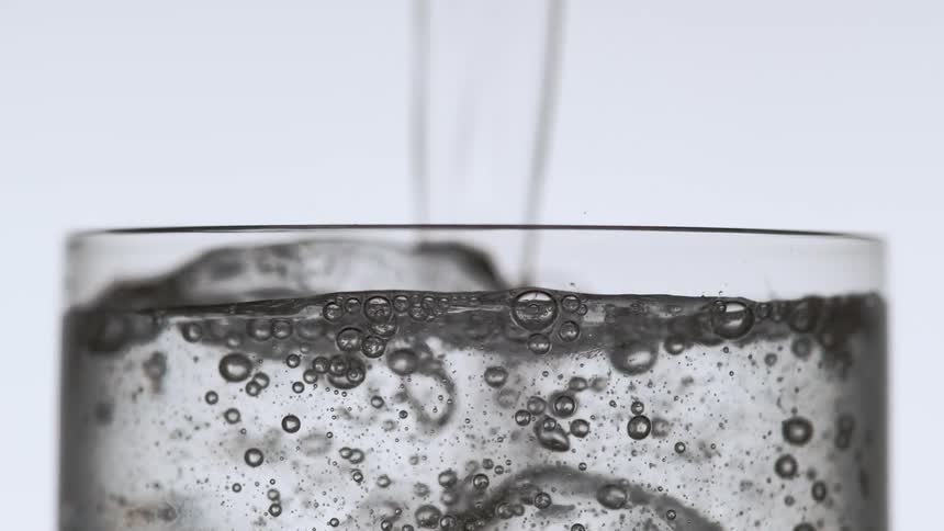 Water is poured into a glass containing ice cubes