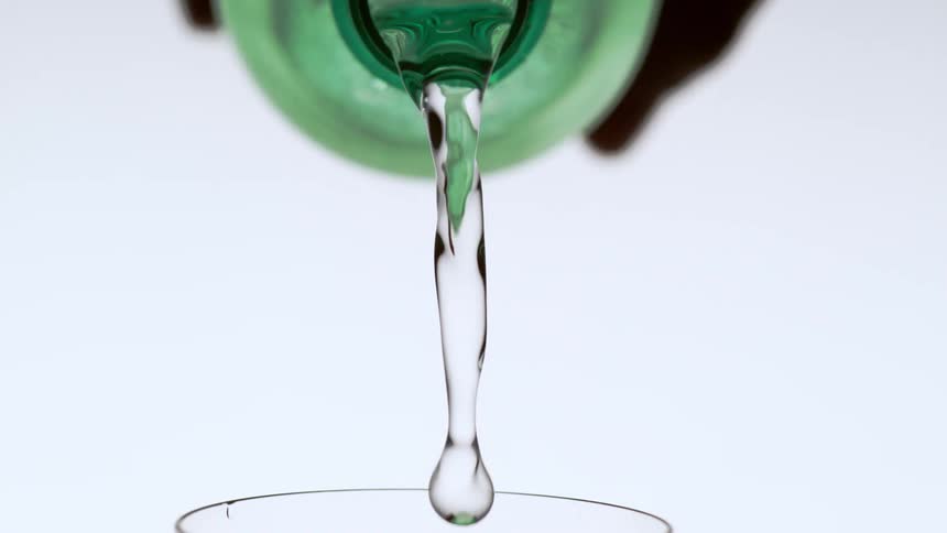 A drink from a bottle is being poured into a glass