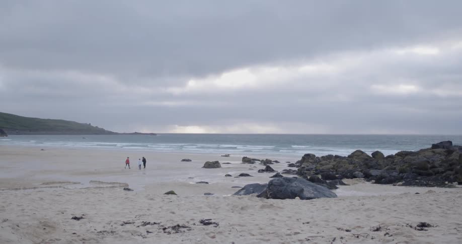 People stand on a beach on a cloudy day