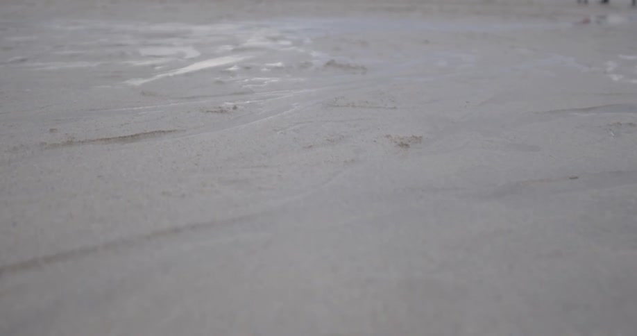 Water cuts paths through beach sand