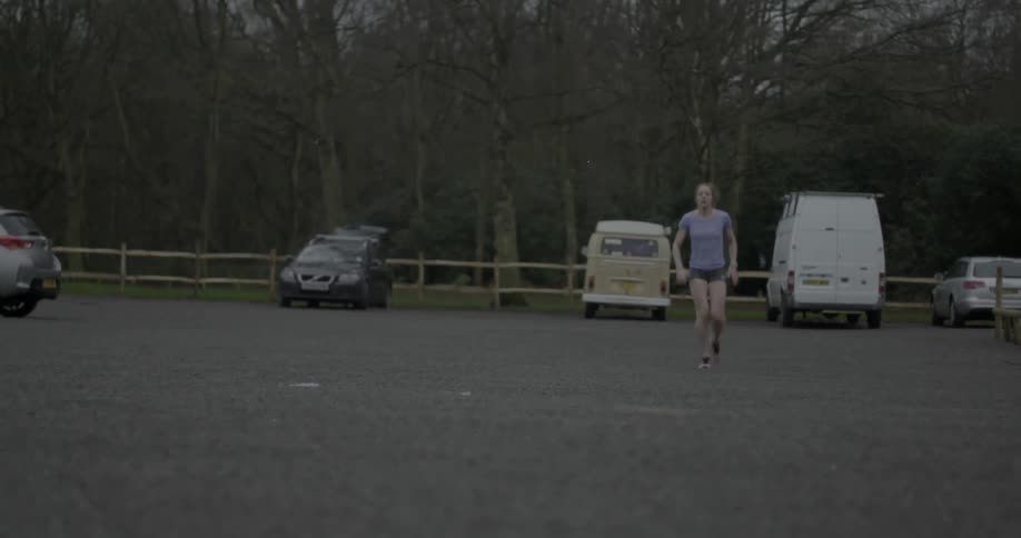 A woman warms up before exercising in a parking lot
