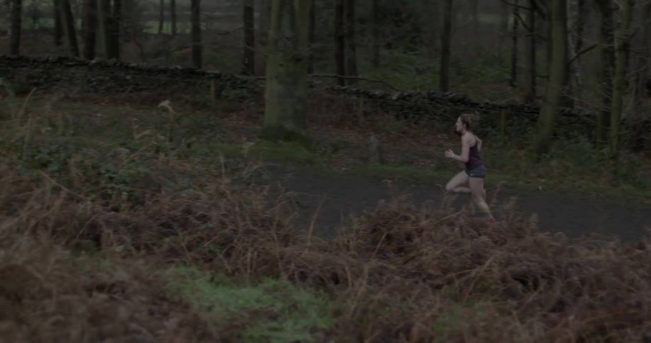 A woman jogging through a wooded area