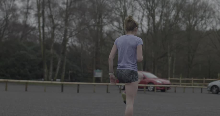 A woman in shorts marches in a parking lot