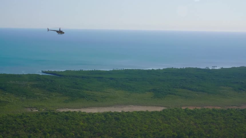 A helicopter flying over a shoreline
