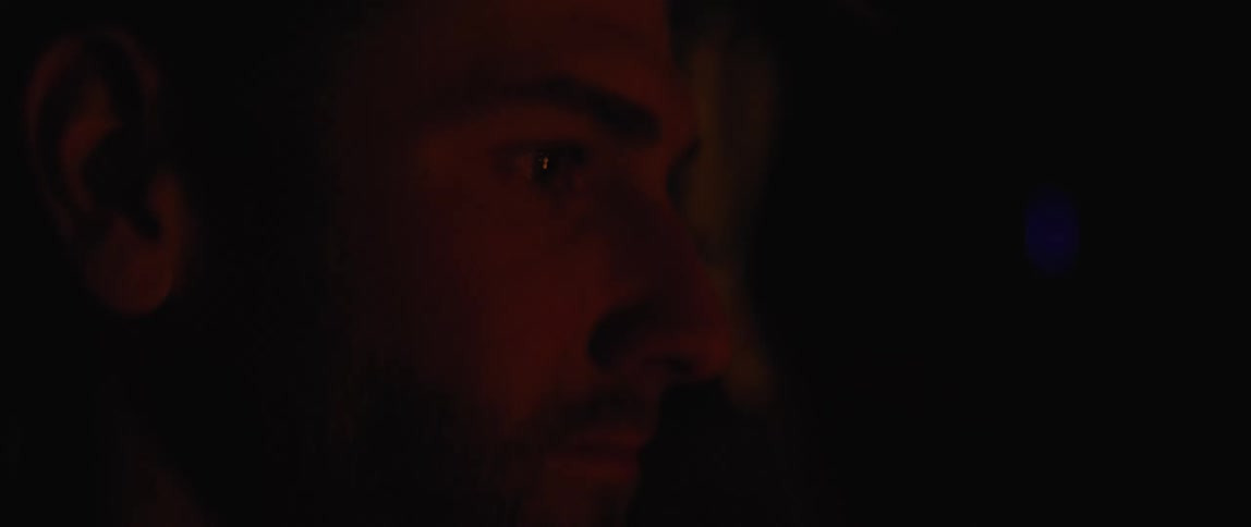Close up of a mans face watching a fire at night
