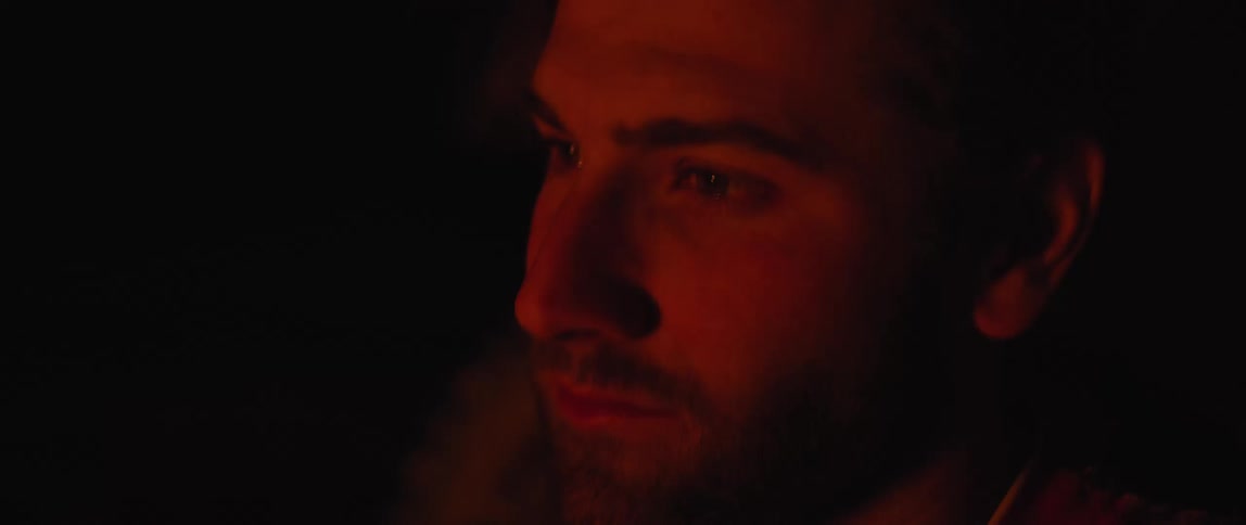 A man blinks by the fire