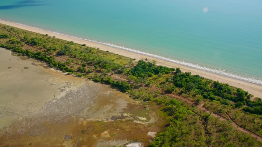 Dirt road runs between fields roughly paralleling beach and ocean