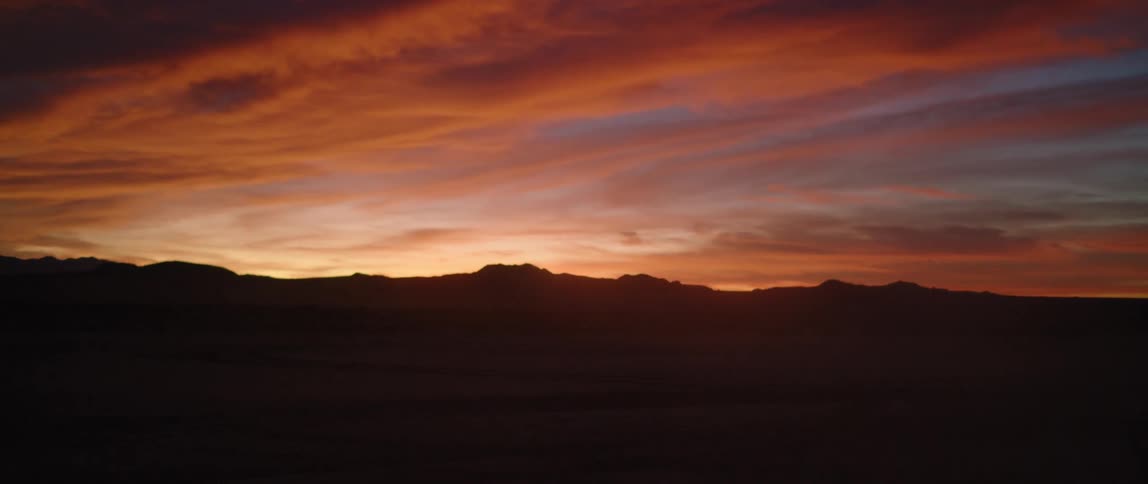 The sky is red as the sun sets over a canyon