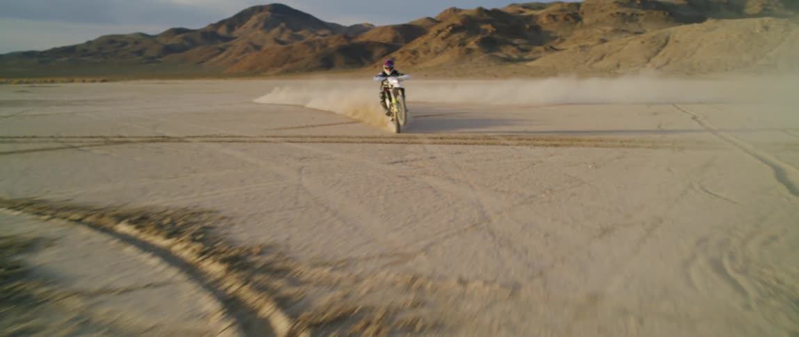 A person rides a motorbike across a desert