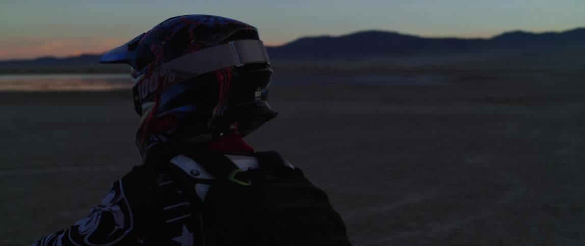 A person sits on a motorcycle in a desert like area and a truck is stopped by him