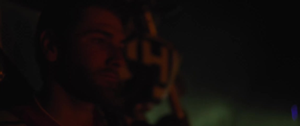 A man is sitting by a motorcycle at night