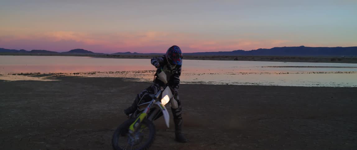 A person spins their dirt bike around by the lake