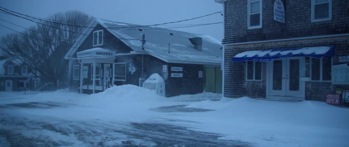 Snow drifts develop along a small village street during a winter storm