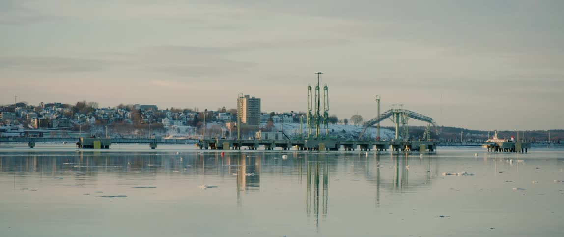 Snow coats a coastal city at sunset during winter
