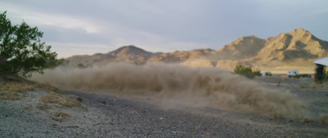 Man drives motocross motorcycle on a dirt road in the desert at sunset