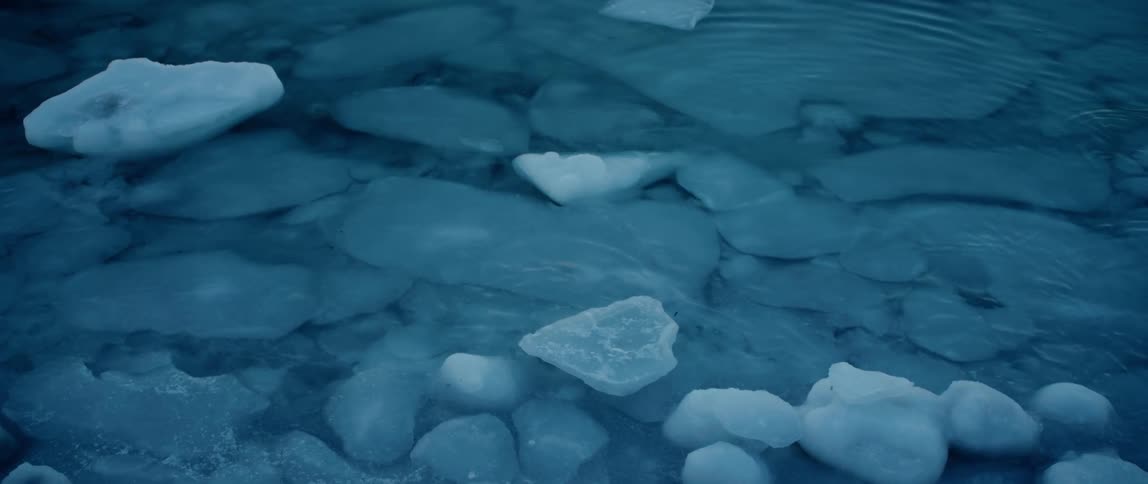 Water ripples around broken ice along the shore