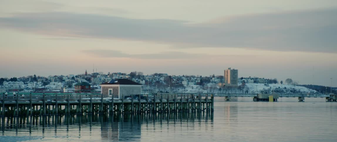 Water ripples around a wooden pier in a coastal city covered in snow