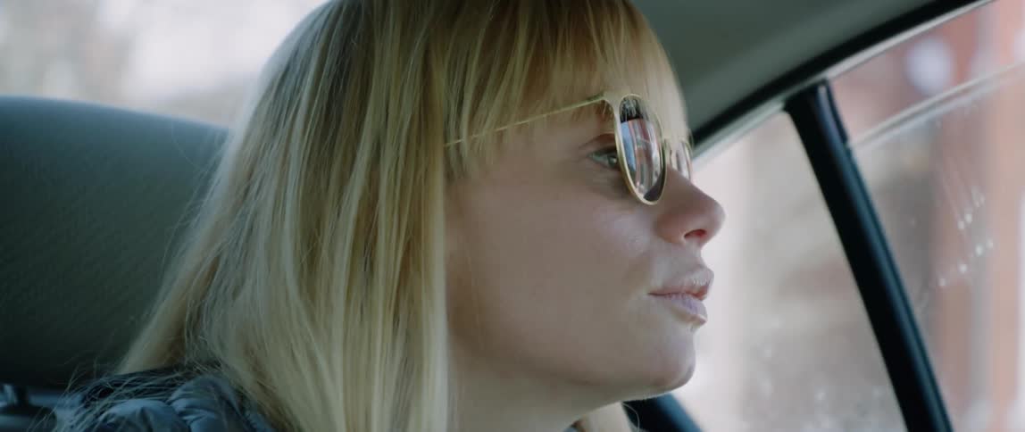 A woman riding in the back of a taxi looks up and out her window
