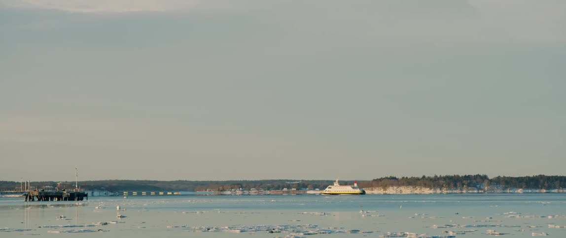 A passenger ferry travels through the icy coastal waters of Portland Maine in winter