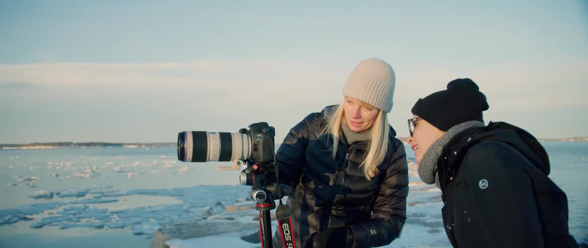 A photographer has her assistant look through her camera at a shot
