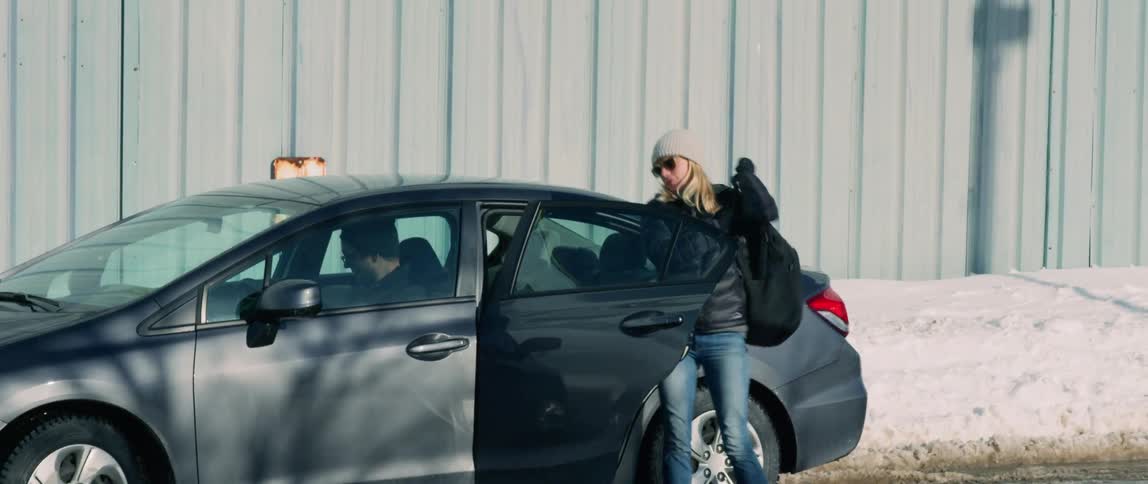 A woman exits a taxi cab with her photography equipment during winter