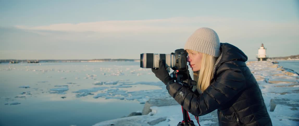 A landscape photographer frames up her shot along the wintery coast