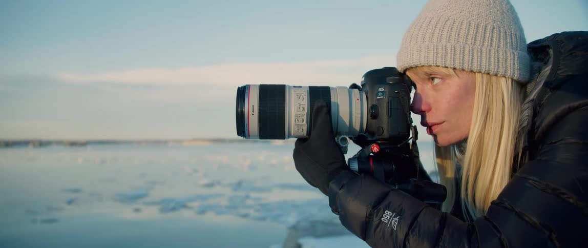 A photographer focuses her shot on a wintery coast