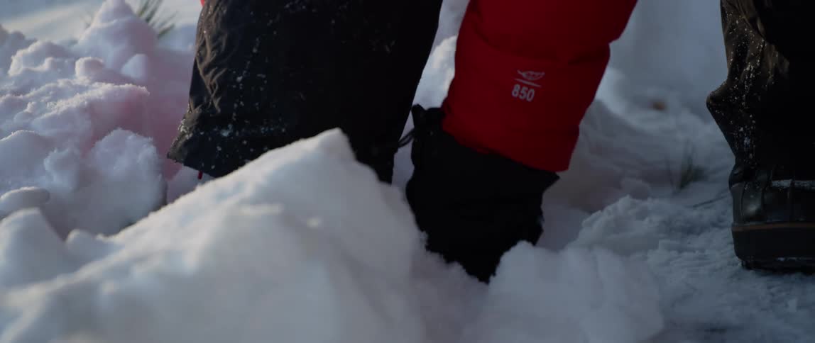 A man straps snowshoes to his duck boots in the snow