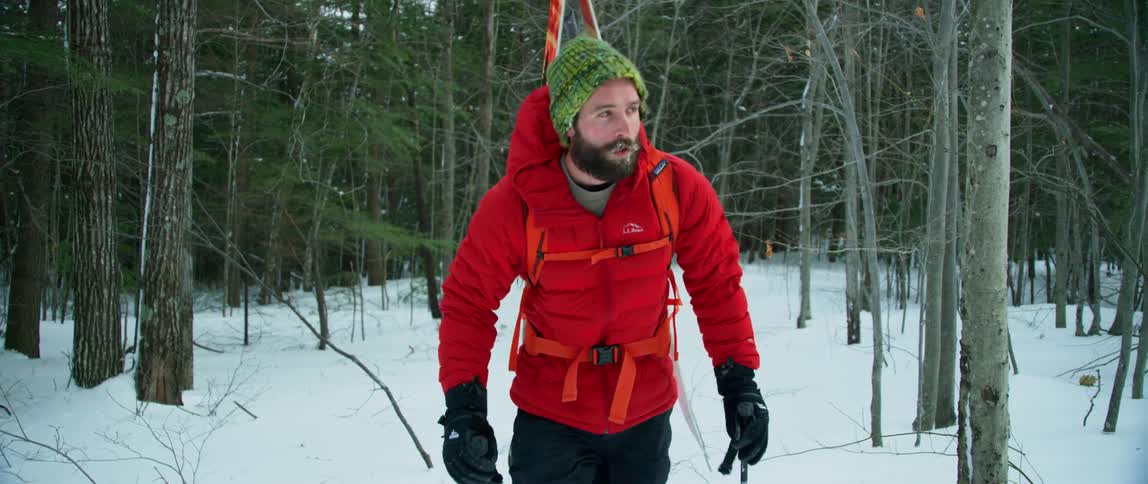 A man with snowshoes treks through woodlands covered in deep snow