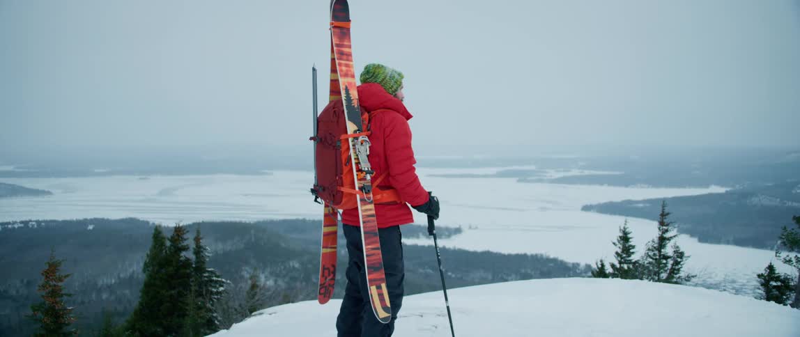 A man completes his hike at the summit of a mountain on a cold winter day