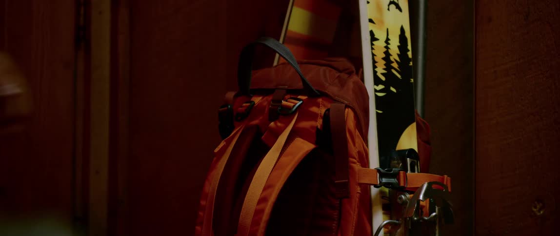 A man quickly grabs a backpack with skis attached to it