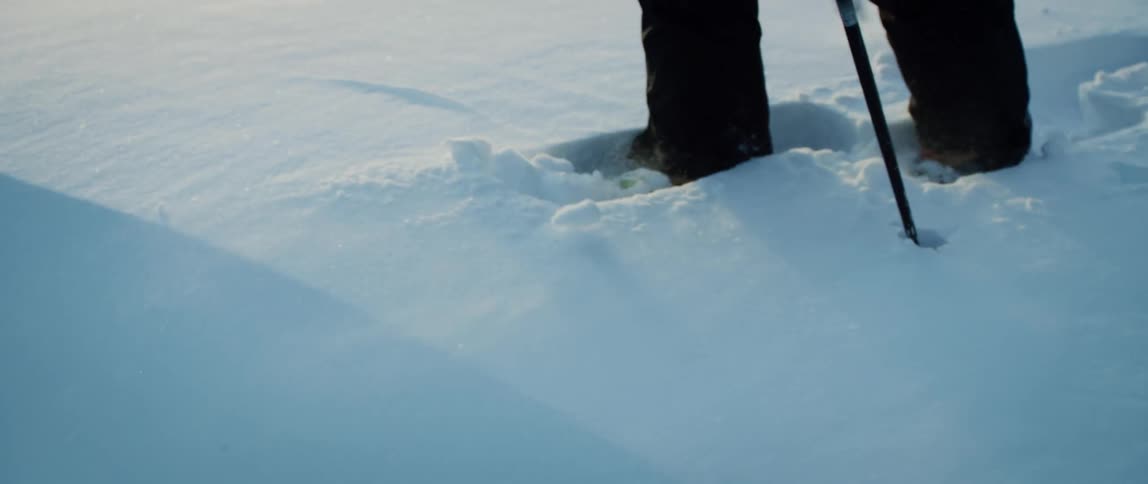 An adventurer snowshoes through powdery snow on a windy winter day