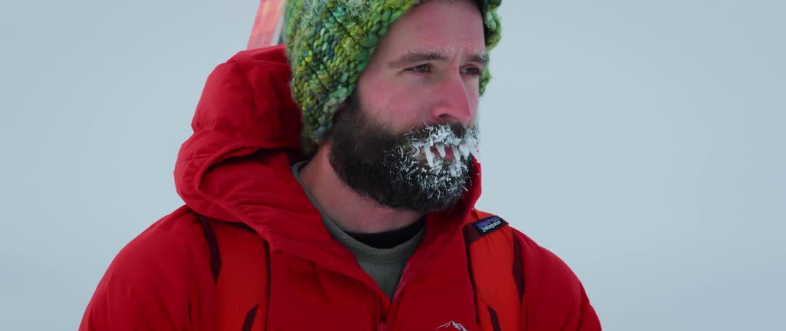 A frozen outdoorsman feels a sense of accomplishment as he looks out from a mountain top