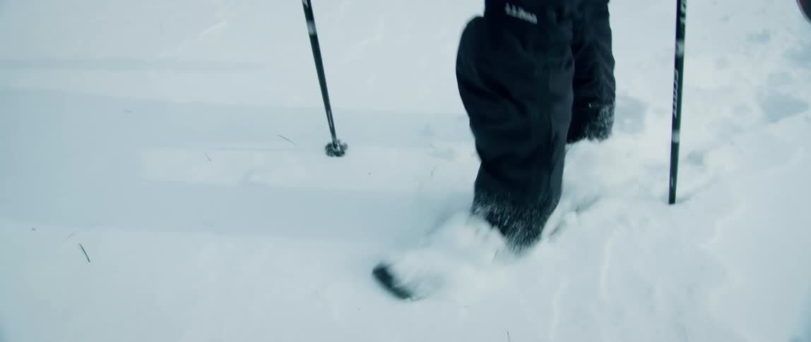 A man trudges through fresh deep snow in the mountains