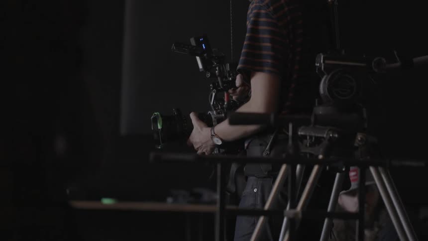 A man films in a dimly lit room