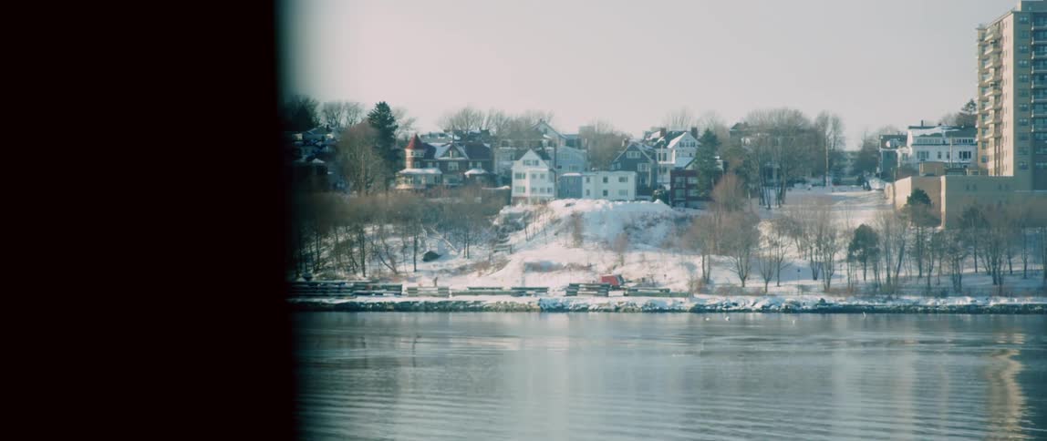 Looking out a ship's window at a wintery coast lined with homes and apartments