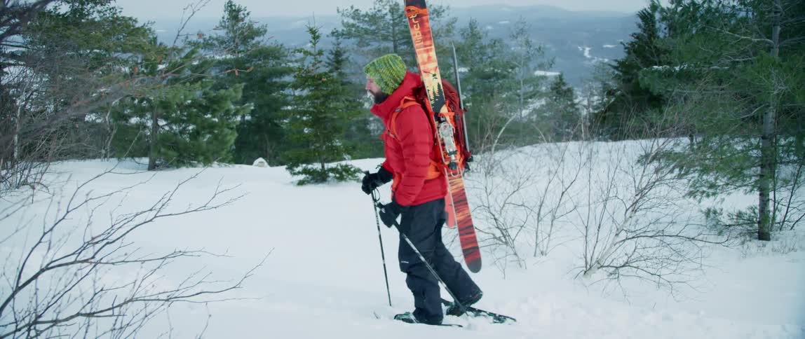An outdoorsman trudges through the snow high in the mountains