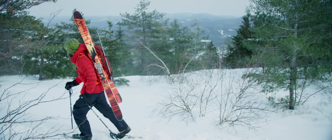 An outdoorsman is hiking high in the mountains on a windy winter day