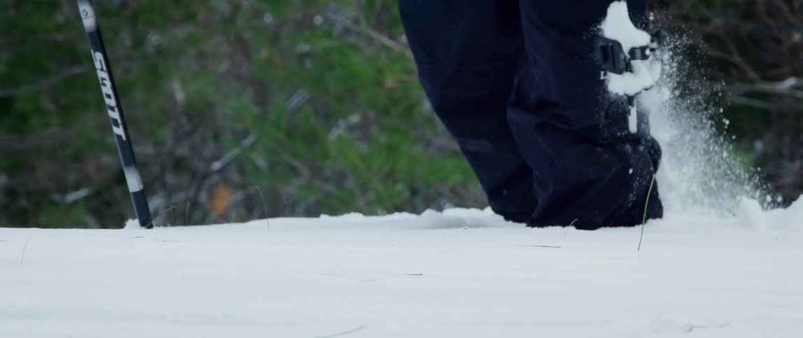 A man snowshoes through deep snow out in the wilderness