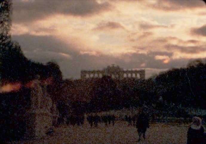 People walk in the Schönbrunn Palace gardens at sunset