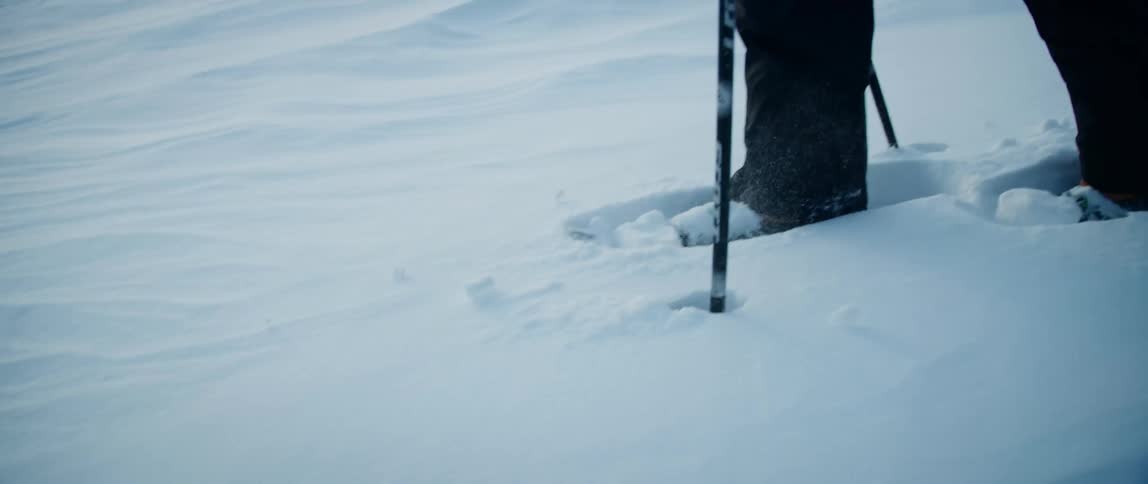 An outdoorsman snowshoes across a frozen snow covered lake